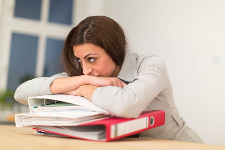 Stressed woman leaning on ring binders