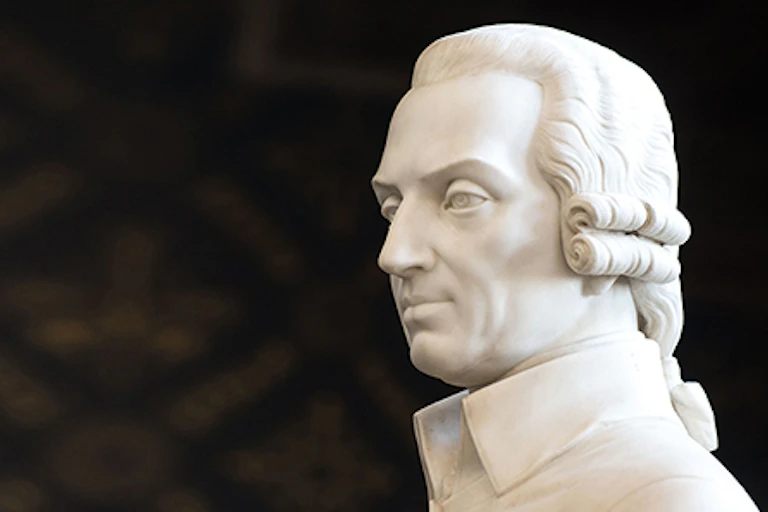 Cropped image of head of white marble statue of a man against a dark background.