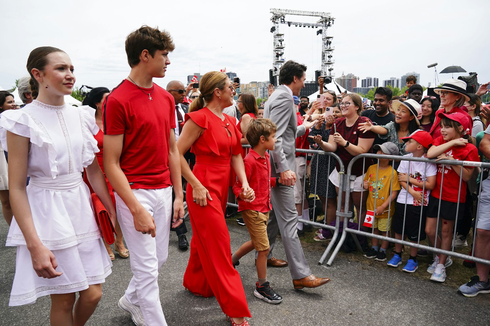 A couple and their three children walk in a line. All are dressed in red or white.