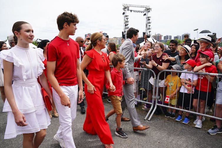 A couple and their three children walk in a line. All are dressed in red or white.