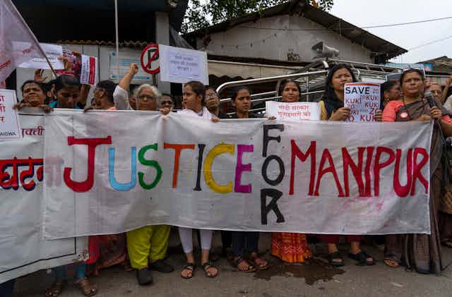 A group of Indian women hold a large banner that reads: Justice for Manipur