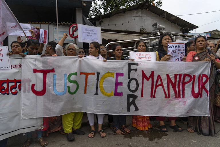 A group of Indian women hold a large banner that reads: Justice for Manipur