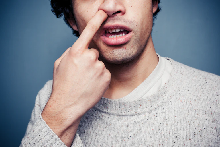 Man sticking finger in nostril