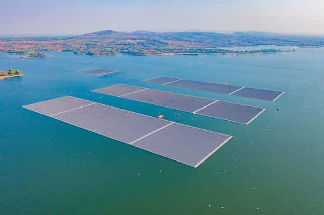 Aerial top view of solar panels or solar cells on buoy floating in lake sea or ocean. 