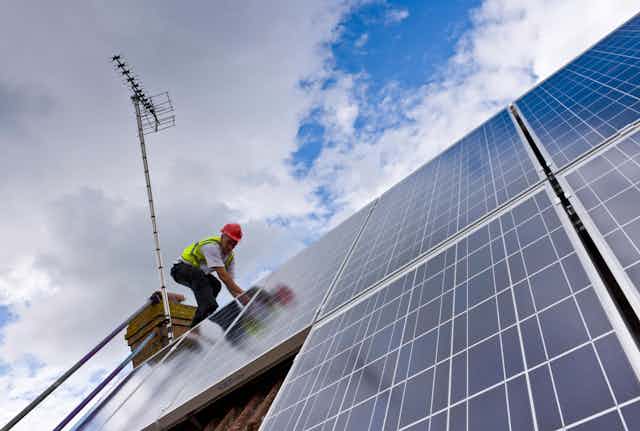 A person installing solar panels on a roof.