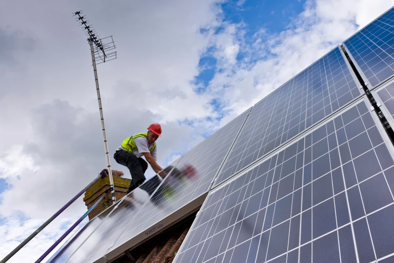 A person installing solar panels on a roof.