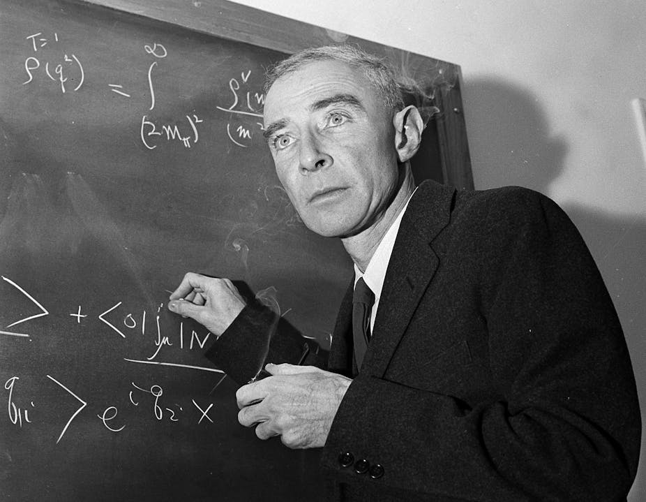 Oppenheimer standing at a blackboard, writing equations in chalk