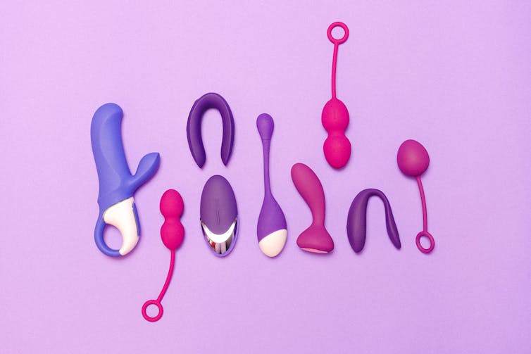 Vibrators and sex toys on pink background.