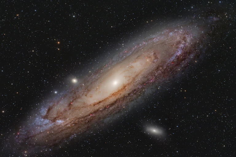 An ovular tan-and-pink galaxy around a bright star.