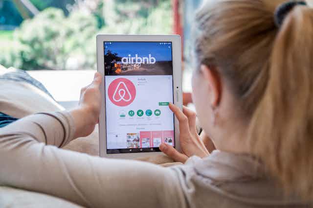 A woman using the Airbnb app on an ipad