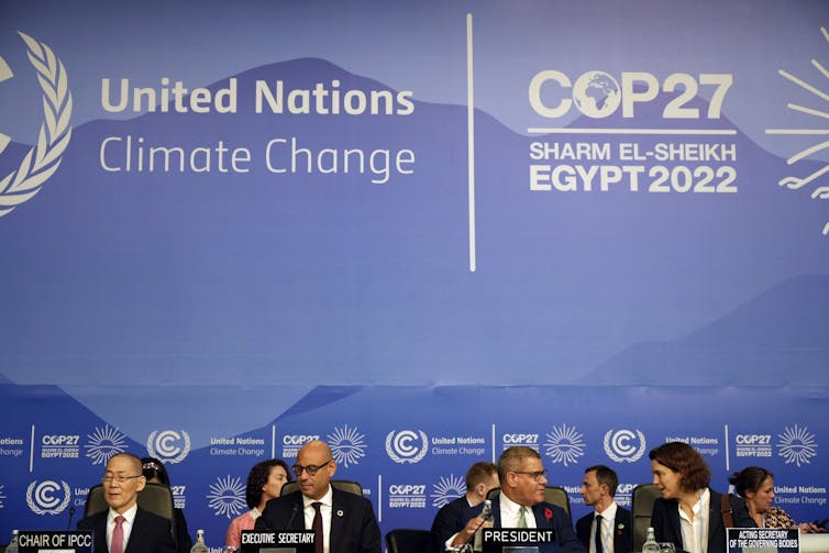 Delegates sit before a banner at COP27