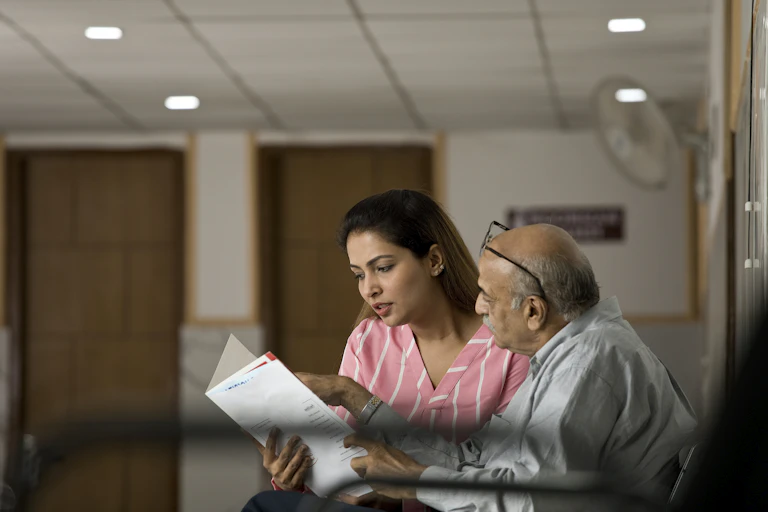 Daughter looking at medical test results with father in hospital waiting room