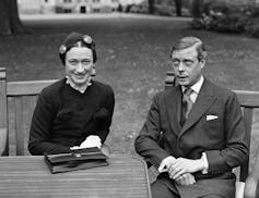 A black and white photo of a man and woman sitting together in a garden.