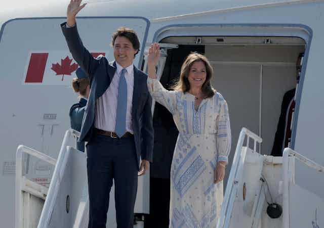 Justin and Sophie Trudeau wave outside an airplane door