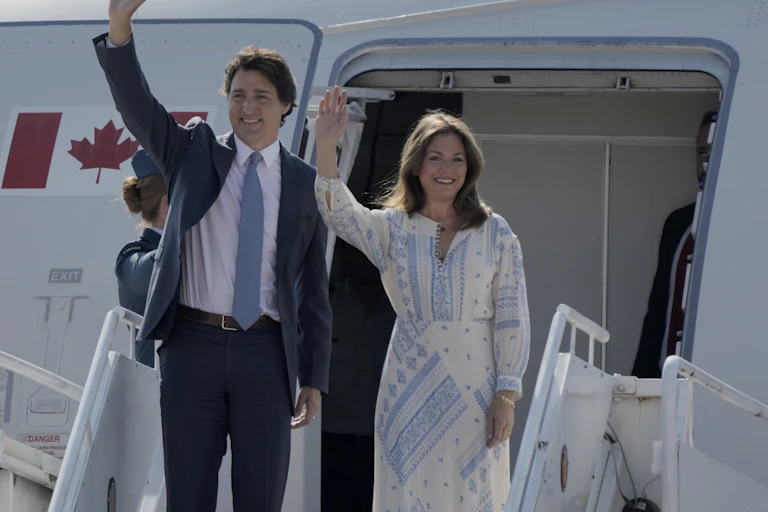 Justin and Sophie Trudeau wave outside an airplane door