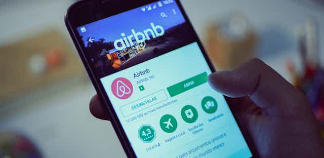 Hand holding smartphone showing Airbnb app.