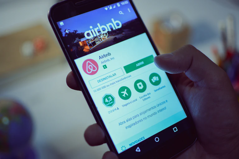 Hand holding smartphone showing Airbnb app.