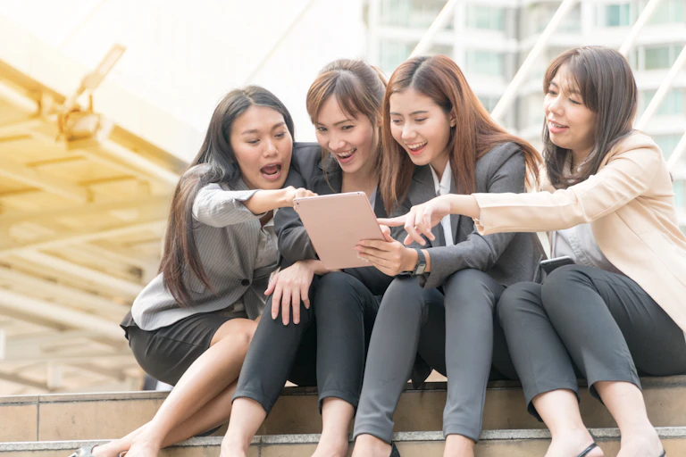 Empat orang dengan pakaian kerja tengah melihat layar tablet.