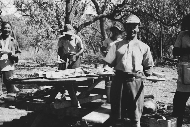 Four men stand around a picnic table.
