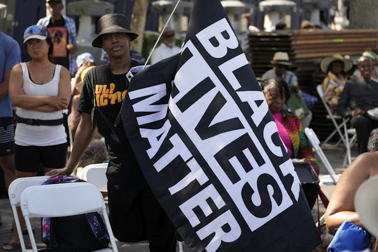 A woman at a demonstration carrying a Black Lives Matter flag.