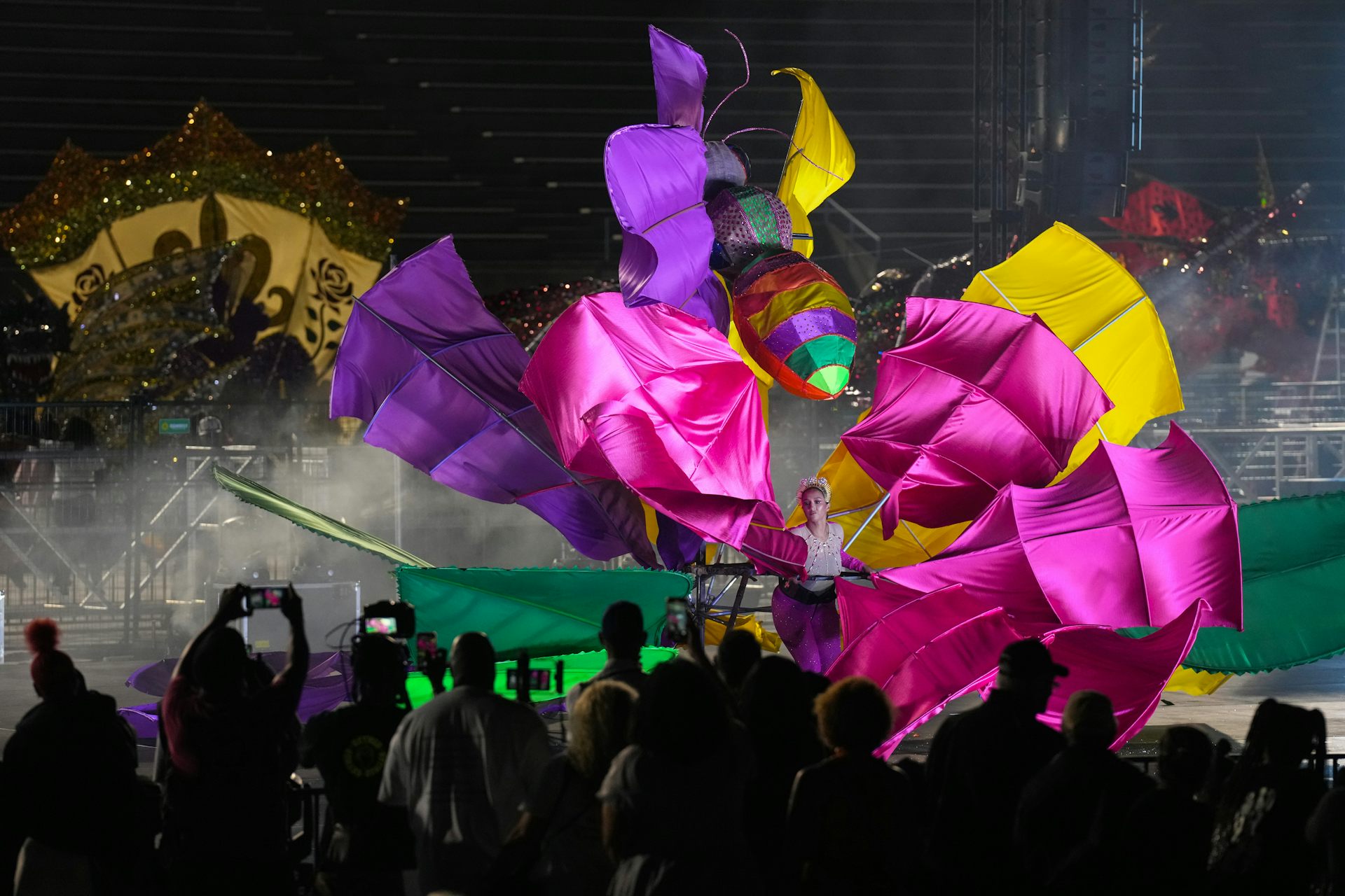 A woman in a large multicolored costume on a stage.