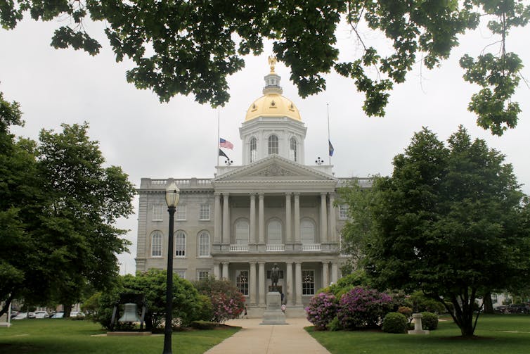 A large two-story granite building with a gold-topped dome.