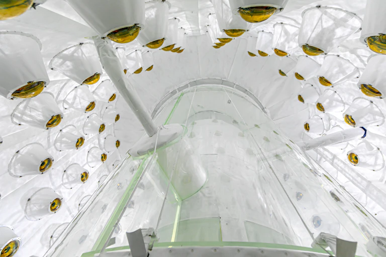 A white chamber filled with spherical orange sensors and a tall cylinder in the middle.
