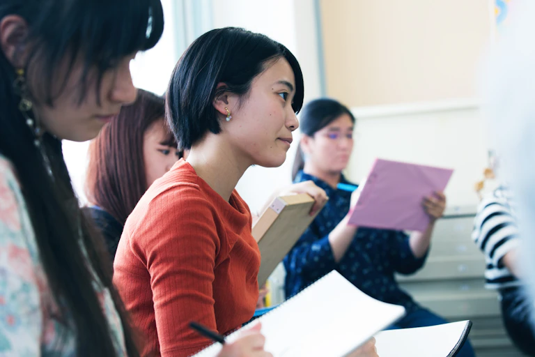 An Asian student is taking notes in class.