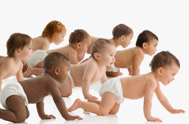 group of diapered babies crawling against white backdrop