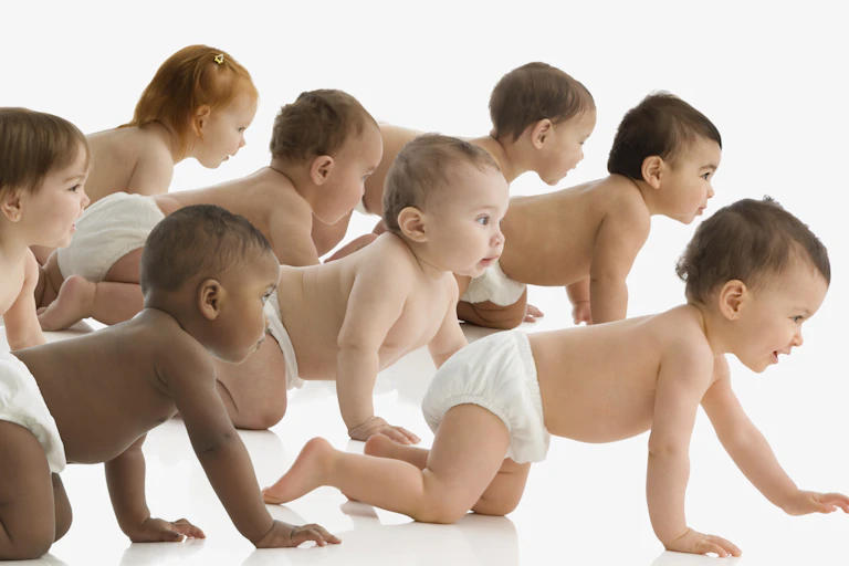 group of diapered babies crawling against white backdrop