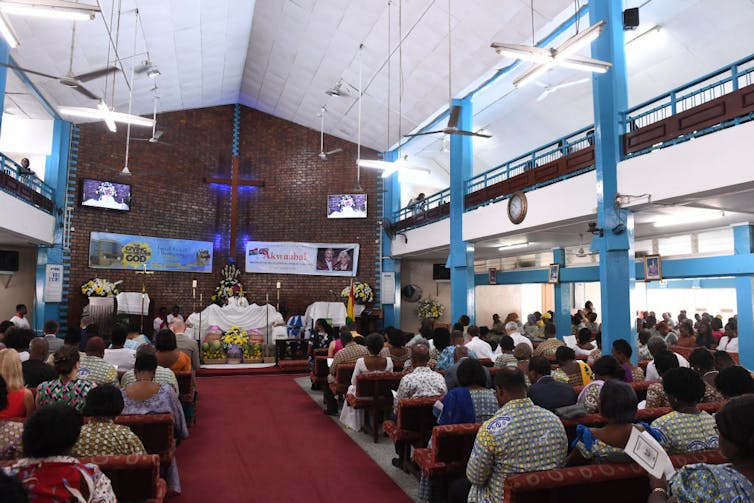 A church sanctuary full of rows of seated people, seen from the back of the room.