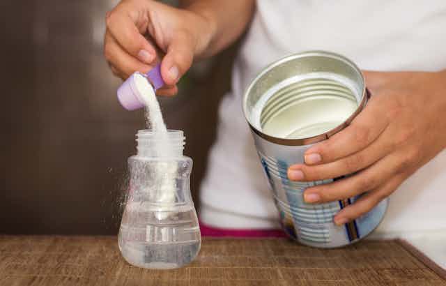 Infant formula being poured into a bottle.