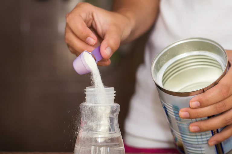 Infant formula being poured into a bottle.