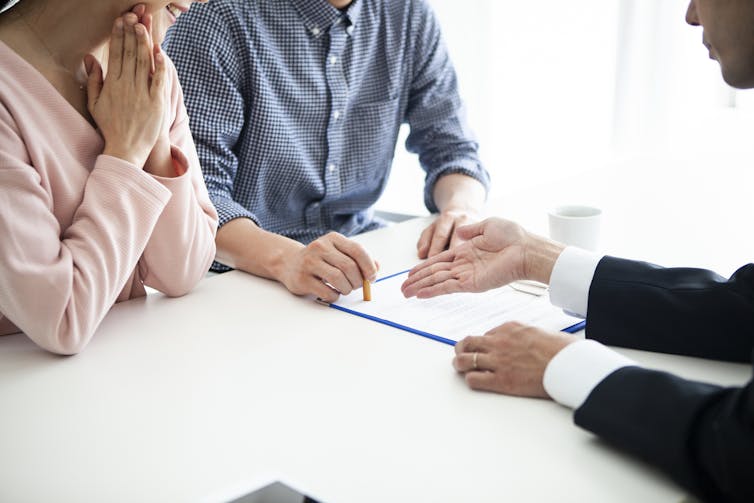 A couple signs a prenup agreement.