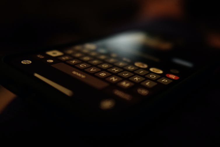 Close-up of a smartphone qwerty keyboard in a dark room