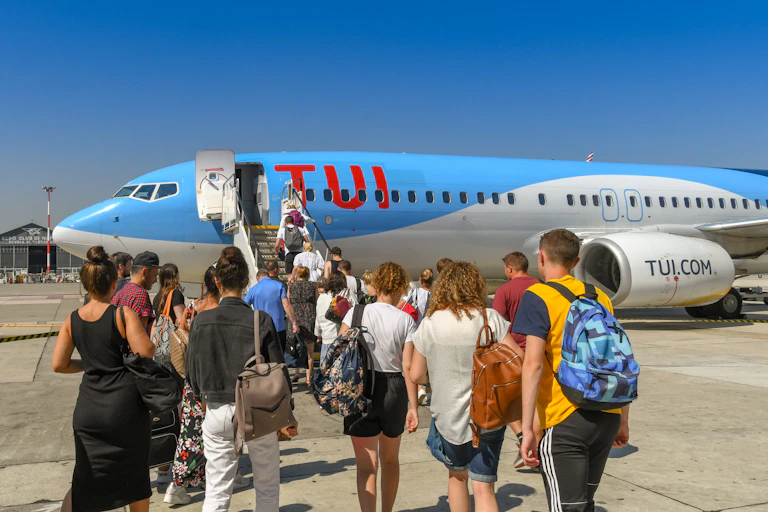 A group of travellers board a plane from the tarmac of an airport.