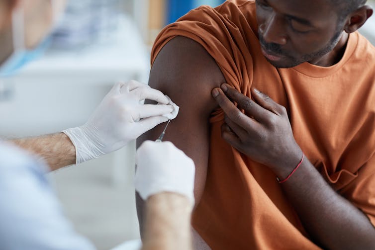 A young man receives a jab from a doctor or nurse.