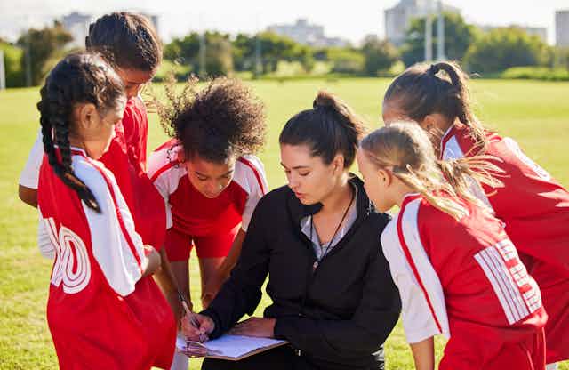 A girls' football team talking with their female coach.