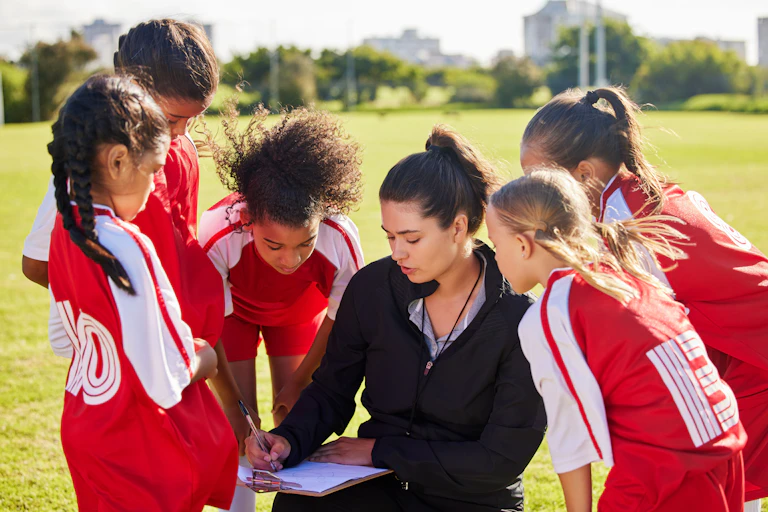 A girls' football team talking with their female coach.