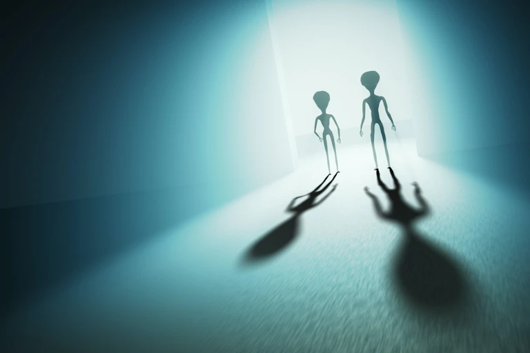 Shadows of two extraterrestrial beings are cut against the light