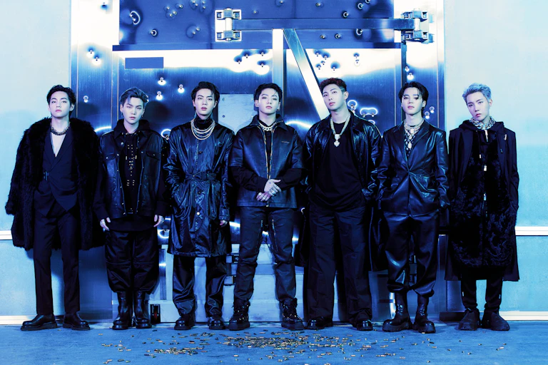 seven young Korean men dressed all in black staring at the photographer.