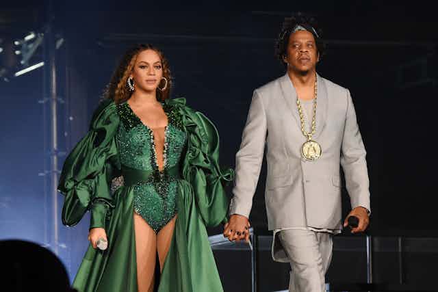 Beyonce and Jay-Z hold hands on stage. 
