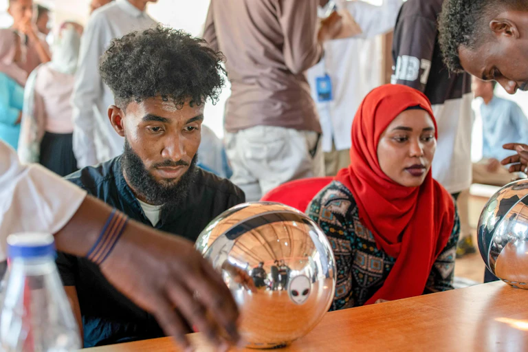 A photo showing two people looking into large silver orbs.