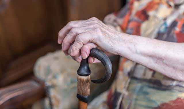 Older person holds a walking stick