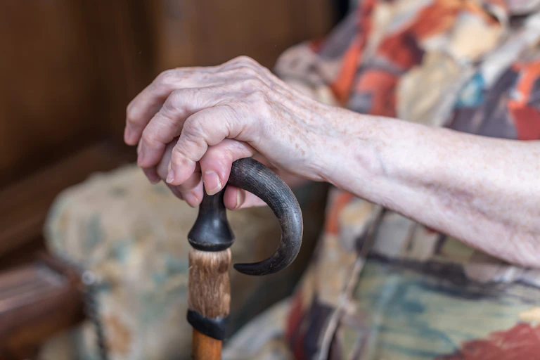 Older person holds a walking stick
