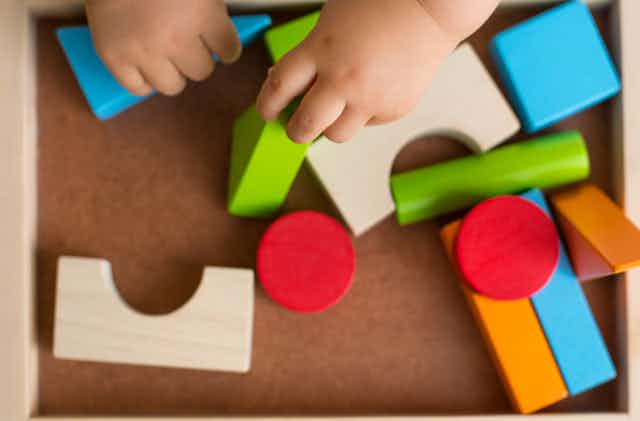 A child plays with blocks in a tray.