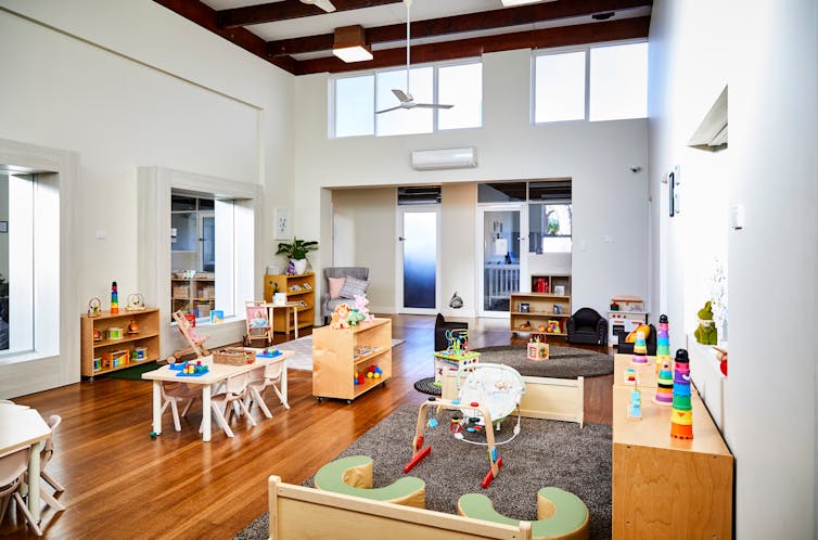 An open plan childcare classroom with desks, shelves and shelves.