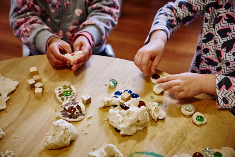 Children play with play-dough and coloured rocks.