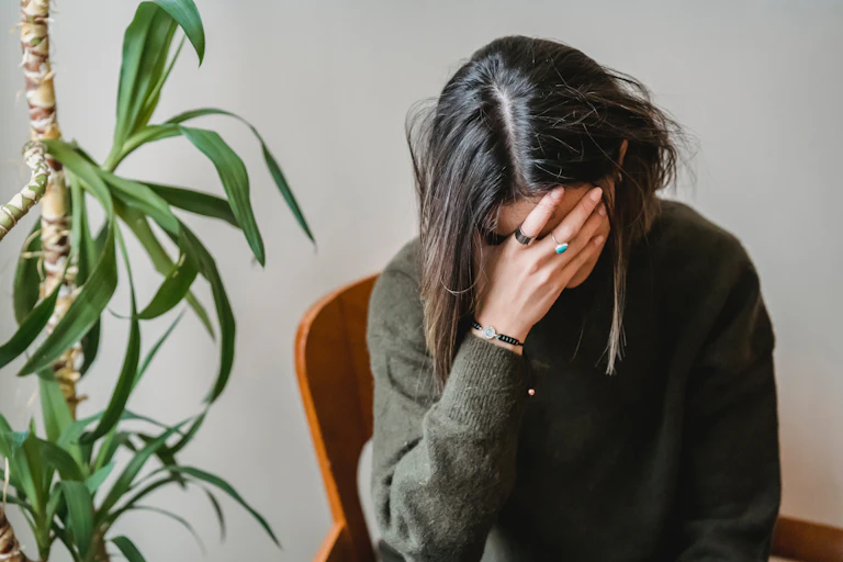 Mid-life woman puts her hand over her face, exhausted