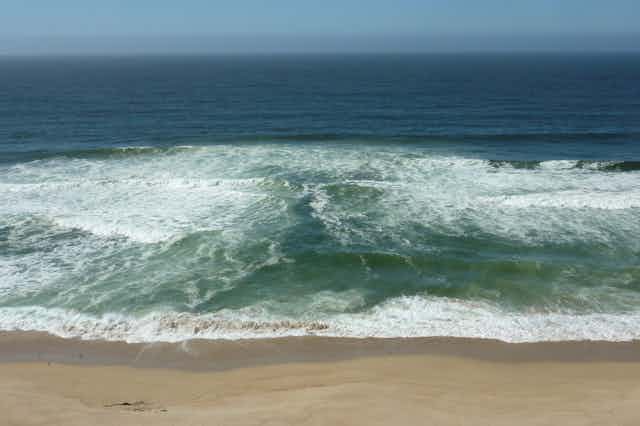 A rip current showing the line of clear water flowing out to sea between the waves